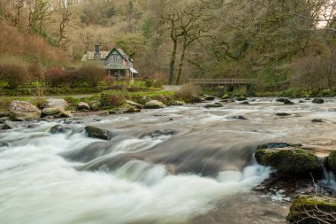 Exmoor Ulusal Parkı 'ndaki Watersmeet evinin önünden geçen Doğu Lyn Nehri manzarası