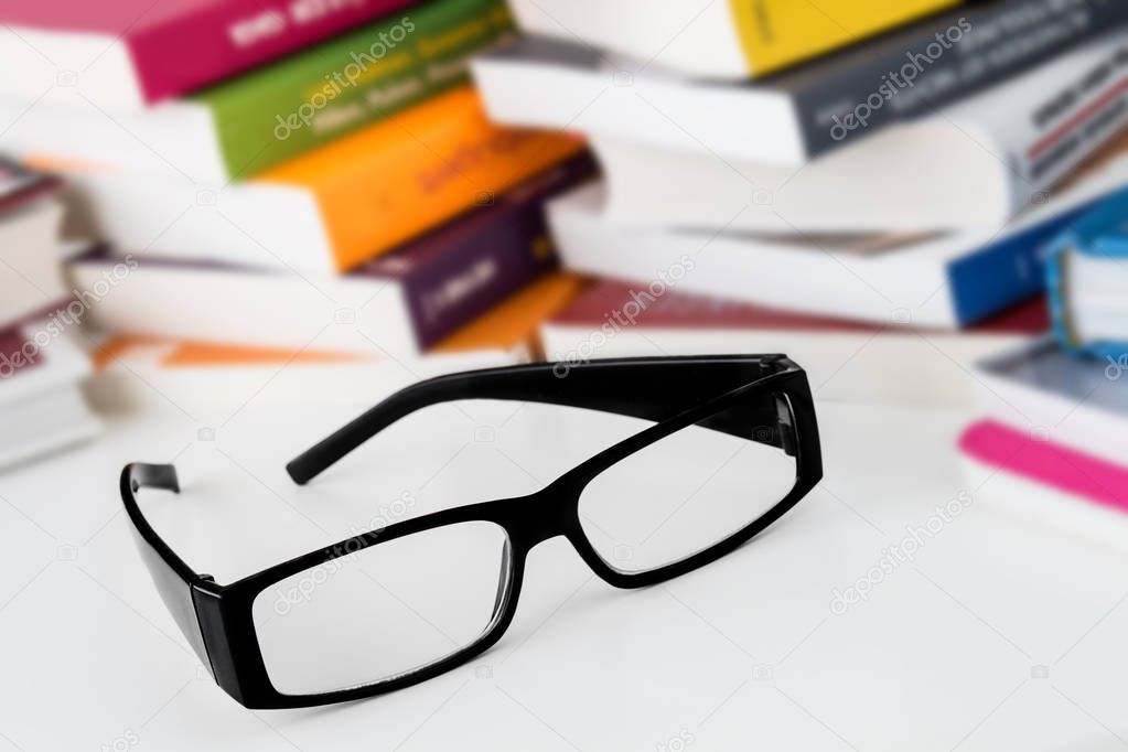 Books and reading glasses on white background