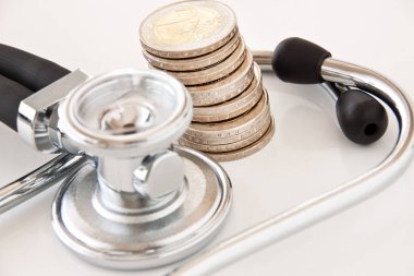 Finance coins and stethoscope on white background clipart