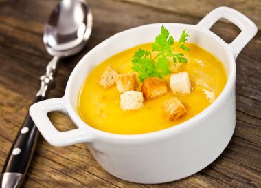 Balkabağı çorbası kasede, kaşıkla yakın plan.