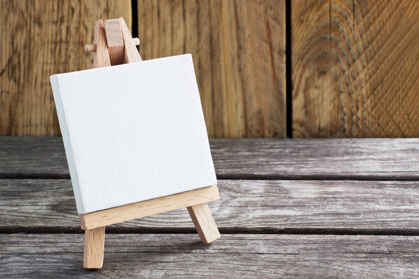Easel on wooden background with copy space