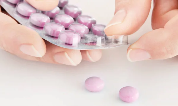 Medikamententabletten im Blister mit männlicher Hand auf weißem Hintergrund — Stockfoto