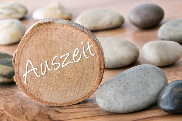 German time-out wooden disc with stones as background