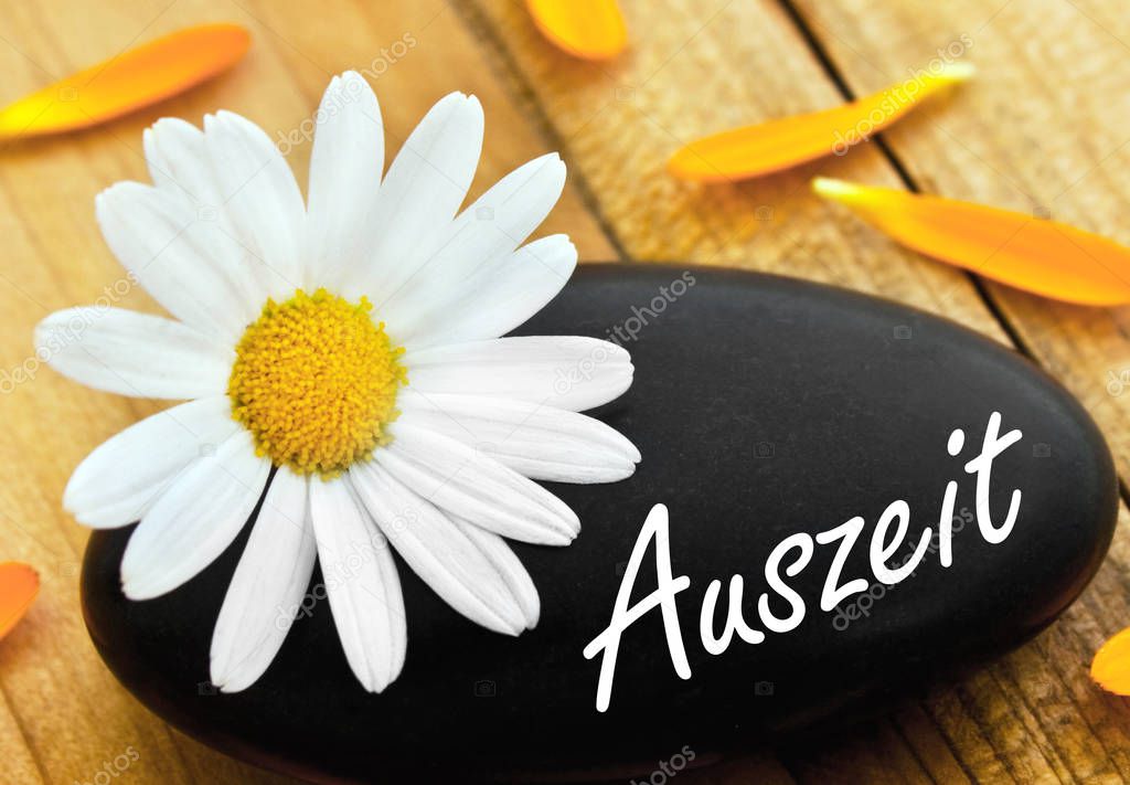 German time-out wellness stone with daisy on wood as background