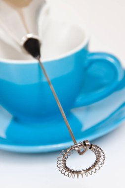 Milk frother and blue cup on white background close-up clipart