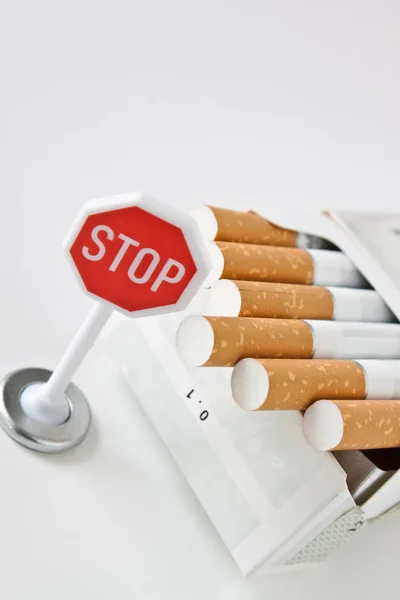 Zigaretten und Stoppschild auf weißem Hintergrund in Nahaufnahme — Stockfoto