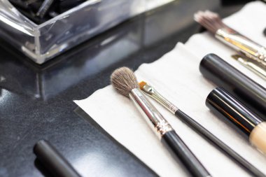Bir makyaj sanatçısının siyah masasına makyaj yapmak için bir sürü farklı fırça. Yakın plan..
