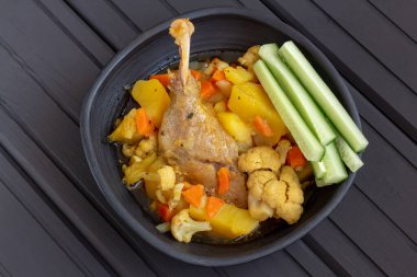 Patatesli ördek budu ve koyu ahşap arka planda, kilden bir kasede taze salatalık. Sağlıklı kırsal yemek.