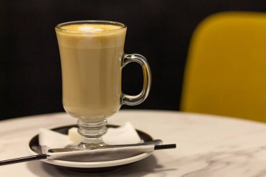 Kahve bardağında Latte, masada pipet ve kahve dükkanında sandalye..