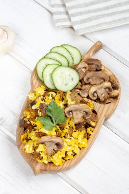 Kavrulmuş yumurta ve mantar (mantar) ve beyaz ahşap arka planda taze salatalık. Üst görünüm, yakın çekim.