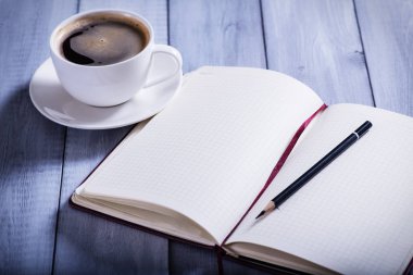 Notebook and cup of coffe  on wooden backgraund