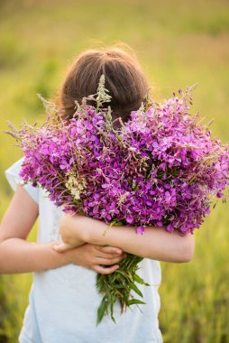 Kız büyük bir demet leylak kokluyor.