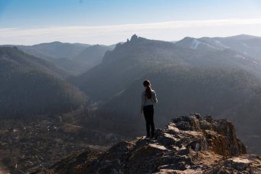 Uçurumun kenarında duran kız mesafeye bakıyor. Manzara, seyahat, yaşam tarzı konsepti.