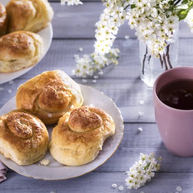 Seramik tabakta tatlı çörekler, beyaz ahşap arka planda çiçek dalları