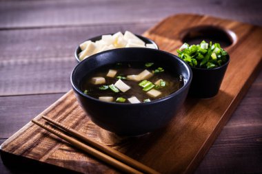 Japon sıcak miso çorbası, ahşap masada siyah bir kase içinde..