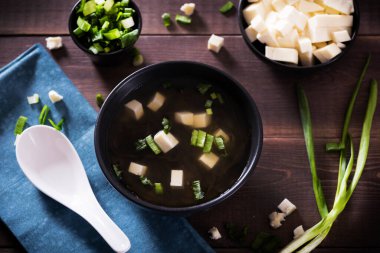 Japon sıcak miso çorbası, ahşap masada siyah bir kase içinde. Yukarıdan yatay görünüm