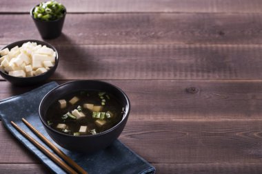 Japon sıcak miso çorbası, ahşap masada siyah bir kase içinde. Yukarıdan yatay görünüm