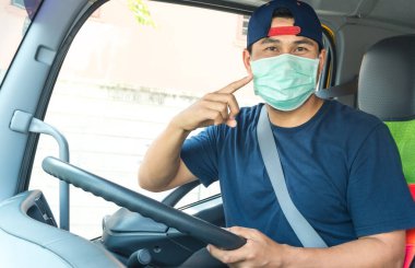 Toza ve gribe karşı korunmak için maske takan Asyalı kamyon şoförlerinin yakın plan fotoğrafları. Covid 19. Arabanın içinde.