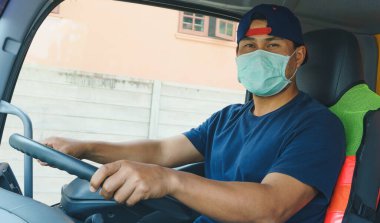 Toza ve gribe karşı korunmak için maske takan Asyalı kamyon şoförlerinin yakın plan fotoğrafları. Covid 19. Arabanın içinde.