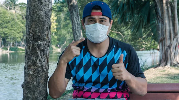 Virüsün yayılmasını önlemek için maske takan genç bir Asyalı. Erkekler virüs salgını yüzünden işsiz..
