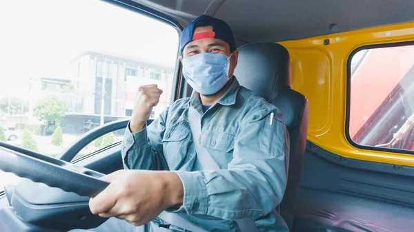 Toza ve gribe karşı korunmak için maske takan Asyalı kamyon şoförlerinin yakın plan fotoğrafları. Covid 19. Arabanın önünde. Engelle savaşmak için yumruğunu tutuyor..