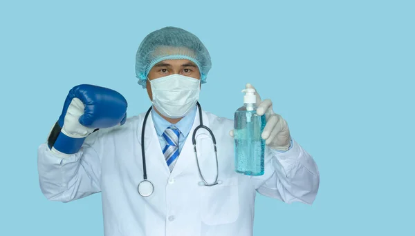 反Covid概念 亚洲医生戴着防护面具 准备动手术 蓝色的背景 洗手用的消毒剂 拳击手套就是打架 — 图库照片