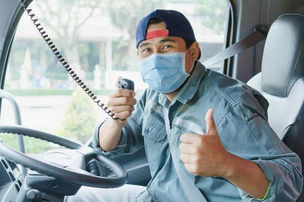 Toza ve gribe karşı korunmak için maske takan Asyalı kamyon şoförlerinin yakın plan fotoğrafları. Covid 19. Arabanın içinde.