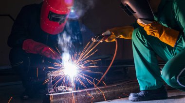 Kaynakçı çeliği fabrikanın içinde bir elektrikli kaynak makinesi ile kaynaklıyor..