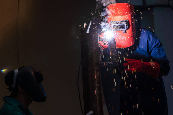 Сварщик сваривает сталь электросварочным аппаратом внутри завода
.