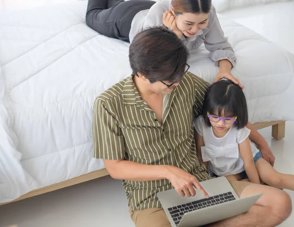 Photos of warm and lovely Asian families. Parents are playing happily and happily with their little daughter in the bedroom. Being happy to be with family on holidays