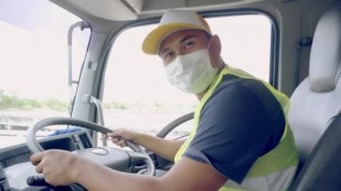 Yeni Normal Konsept - Kamyon şoförü havaya toz ve virüslerin yayılmasını önlemek için tıbbi maske takıyor.