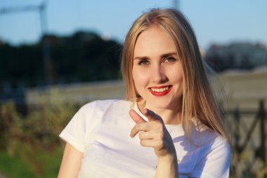 Genç sarışın kadın kameraya işaret ediyor