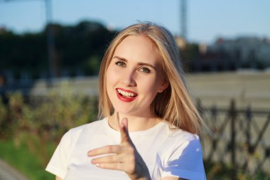 Genç sarışın kadın kameraya işaret ediyor