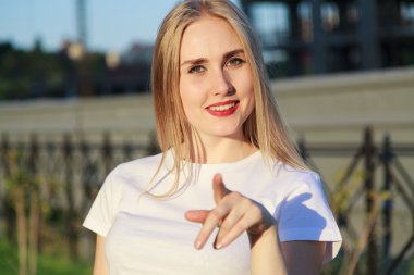 Genç sarışın kadın kameraya işaret ediyor