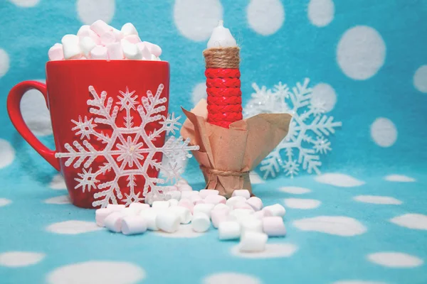 Guimauve dans une tasse à côté de bougies et de flocons de neige — Photo