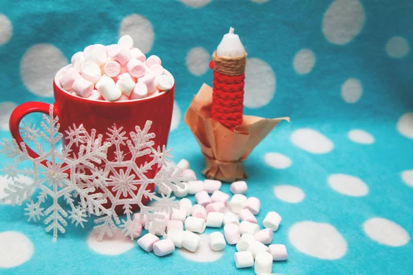 Guimauve dans une tasse à côté de bougies et de flocons de neige — Photo