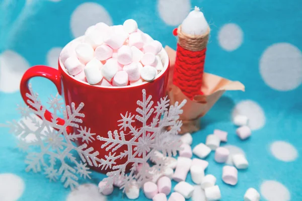 Guimauve dans une tasse à côté de bougies et de flocons de neige — Photo