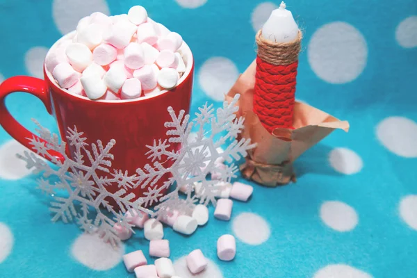 Guimauve dans une tasse à côté de bougies et de flocons de neige — Photo