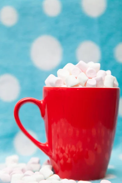 Guimauve dans une tasse rouge sur un fond bleu — Photo