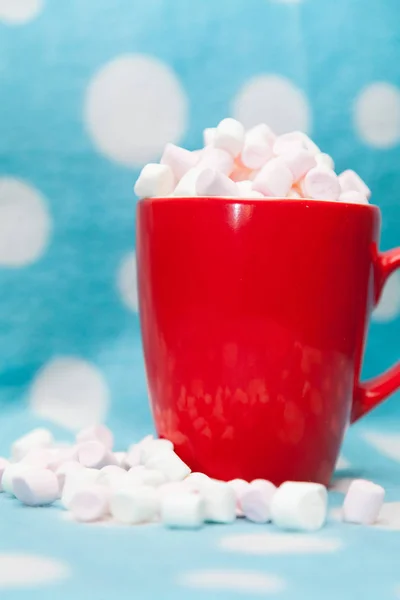 Guimauve dans une tasse rouge sur un fond bleu — Photo