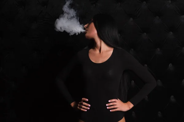 Сексуальная брюнетка курит электронную сигарету — стоковое фото