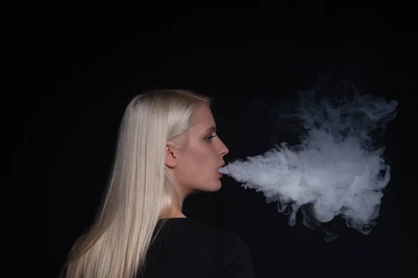 年轻的金发女子吸烟电子烟释放蒸汽从嘴里 — 图库照片