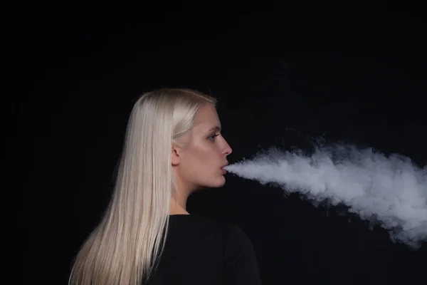 Молодая блондинка курит электронную сигарету выпуская пар изо рта — стоковое фото