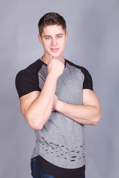 Young athletic man in a T-shirt on a gray background — Stock Photo, Image