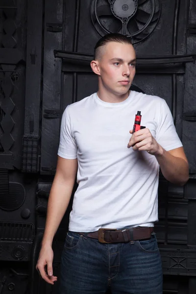 Mec en t-shirt blanc fumant une e-cigarette sur un fond noir — Photo