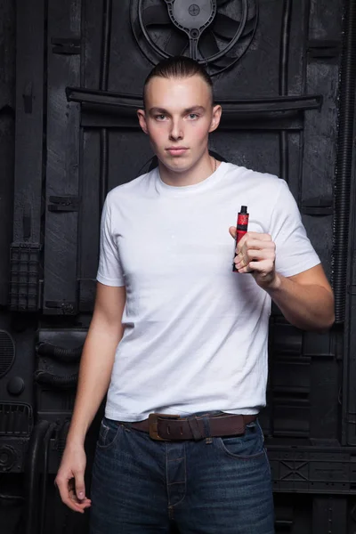 Mec en t-shirt blanc fumant une e-cigarette sur un fond noir — Photo