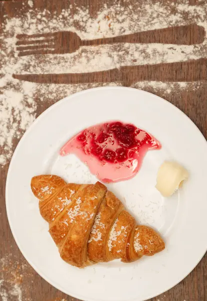 It lies on a plate with croissants, jam and butter — Stock Photo, Image