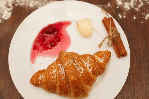 It lies on a plate with croissants, jam and butter — Stock Photo, Image