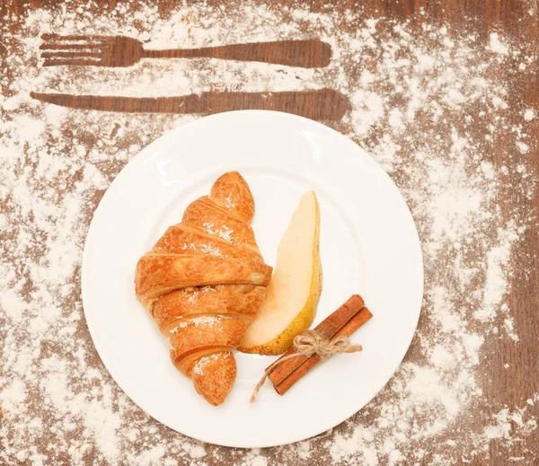 pear and croissant in coconut chips are a wooden background