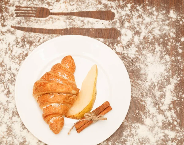 pear and croissant in coconut chips are a wooden background